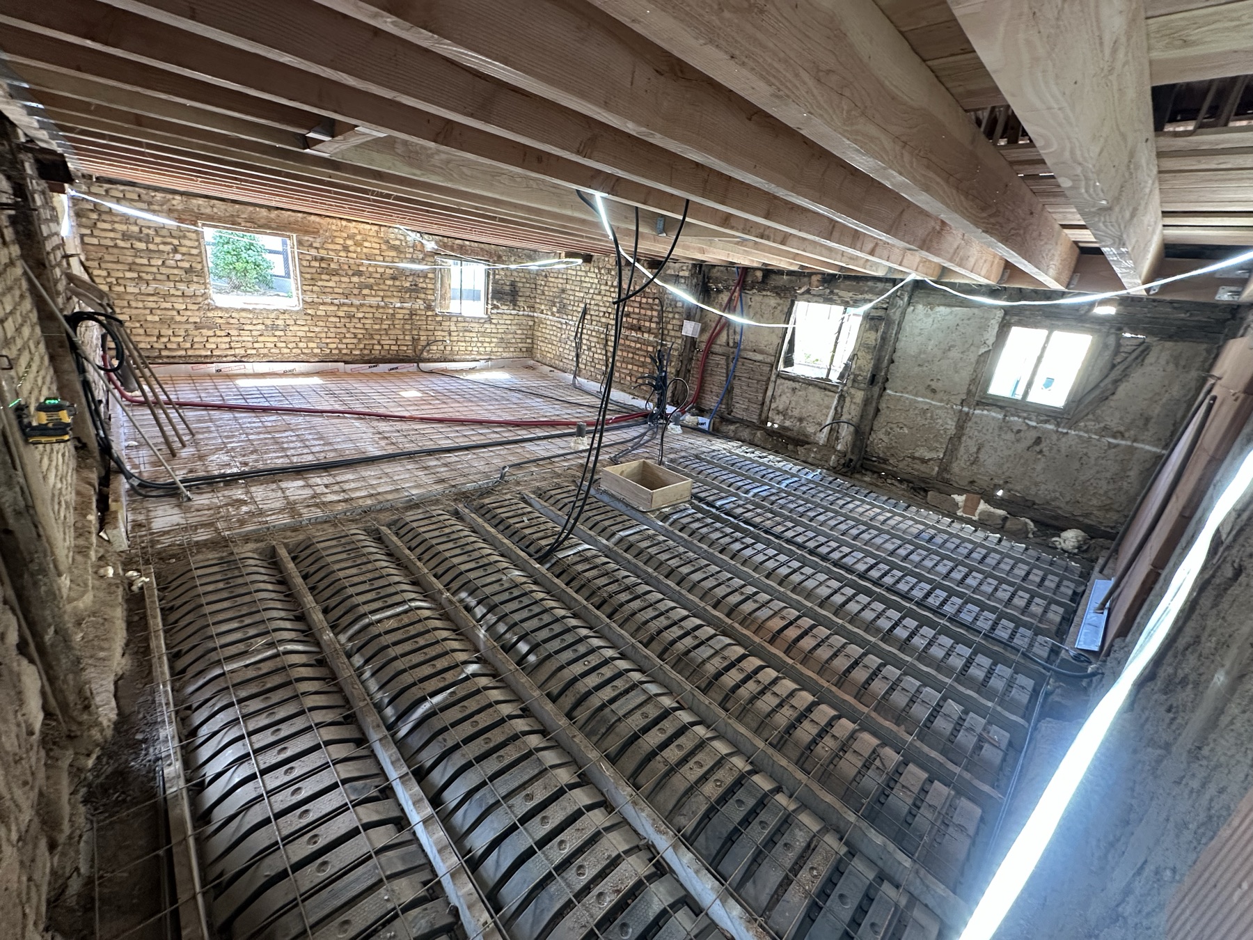 Le même séjour à l'état brut : briques, charpente apparente et plancher en cours